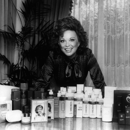 Paula Kent in black in white in front of original redken products.